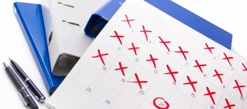 A calendar with dates marked off in red crosses, sits on top of folders.