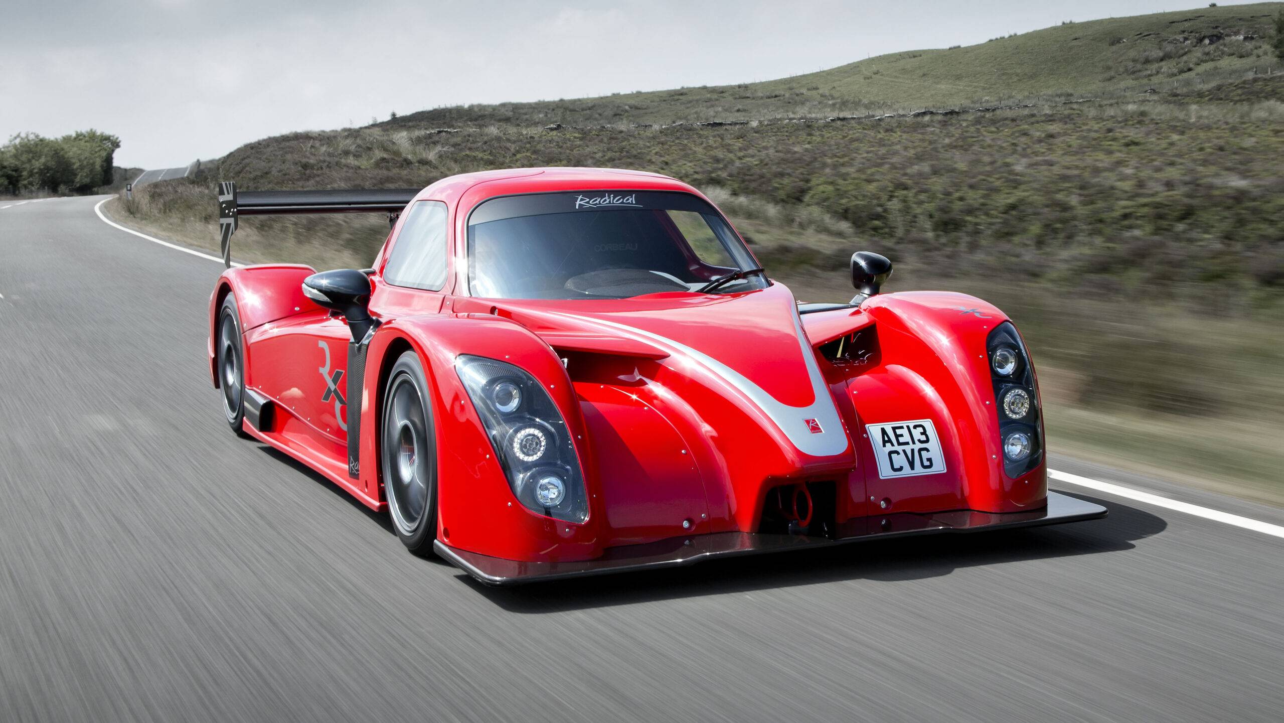A Radical RXC GT in red driving on a road.