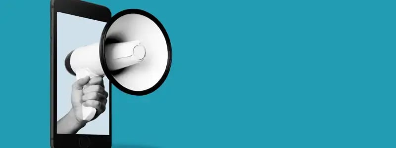 A hand holding a megaphone coming out of a phone, representing reach on mobile devices.
