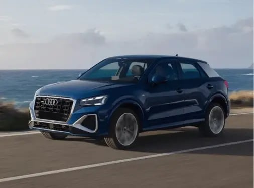 A blue Audi Q2 driving on a coastal road.