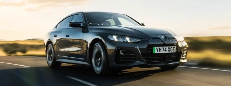 A black BMW i4 driving round a corner at speed, with the background blurred.