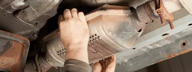 An SUV's catalytic converter being removed at a salvage yard.
