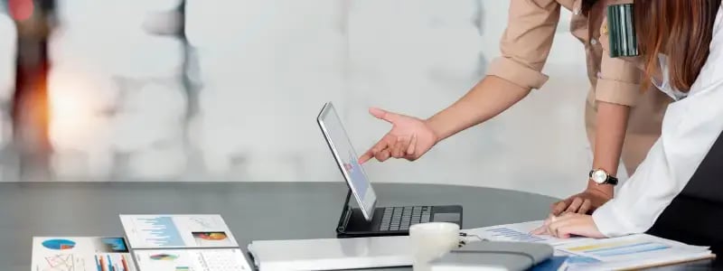 Two people looking at graphs in a business setting.