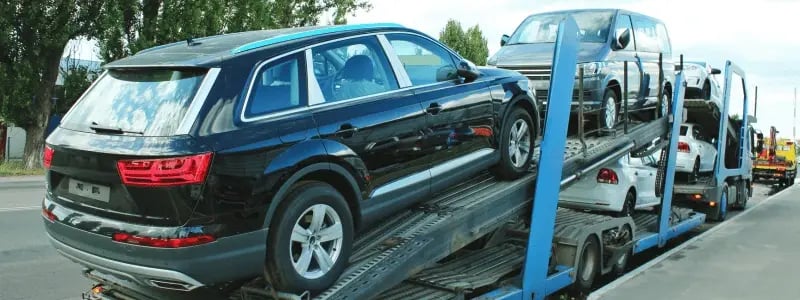 Cars loaded onto a delivery lorry, parked at the side of a road.