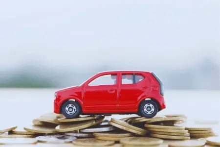 A toy car on top of a stack of coins, representing finances and cars.
