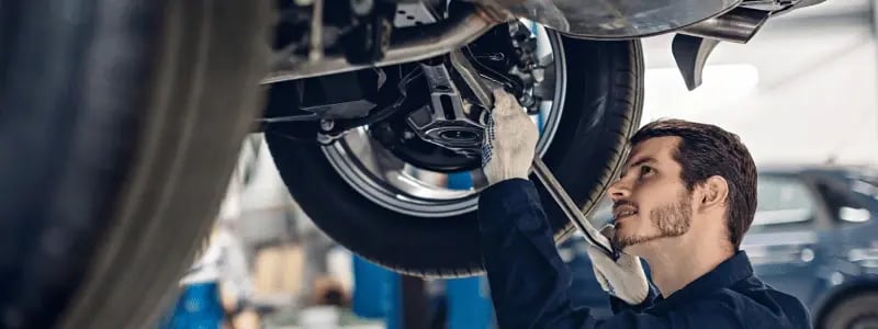 A person working on the underside of a car.