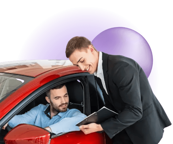 A car salesman assisting a customer while sat in a car.