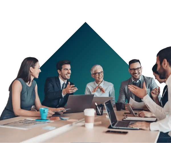 People in a work setting having a discussion around a table, with a geometric triangle in the background.