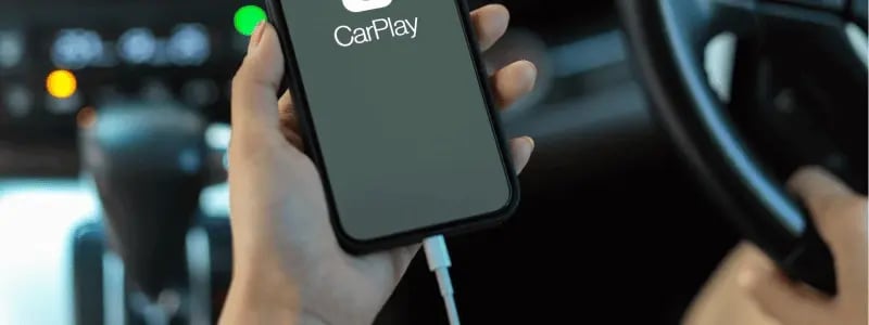 A phone cable connected a phone displaying the Apple CarPlay app.