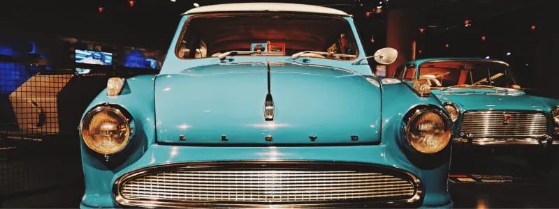 A light blue classic car in the showroom with other classic cars.