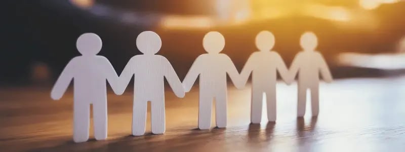 Cardboard people cut-outs in a line, symbolising togetherness.