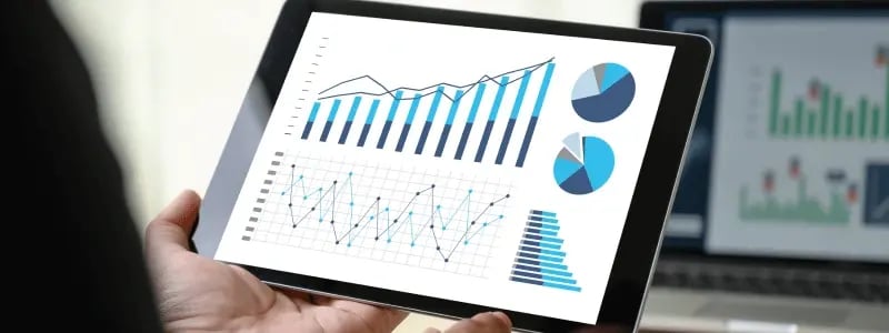 A person looking at various forms of data on a tablet device, inlcuding pie charts and bar graphs.