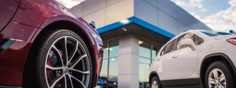Two cars parked in front of a dealership in day time.