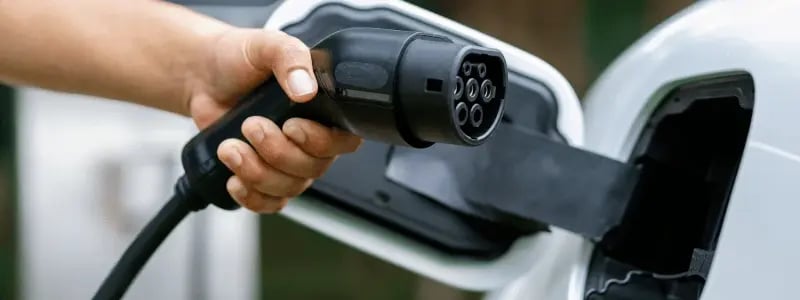A close up of an electric charging cable being plugged into an electric vehicle.