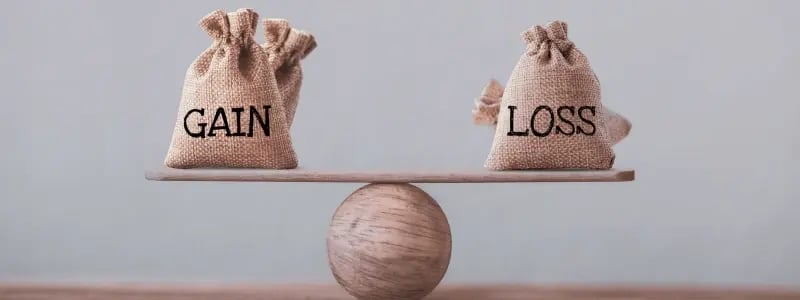 Wooden scales with money bags at each side, one saying 'GAIN' and the other 'LOSS', representing the balancing act in finances.
