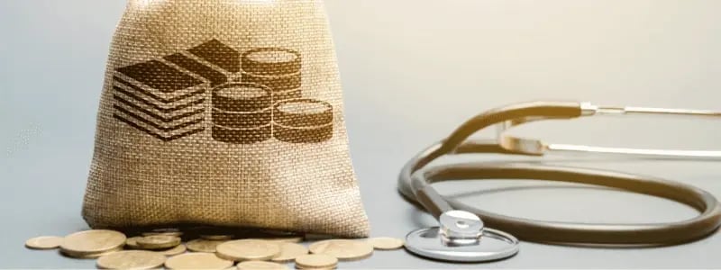 A bag of money with coins below it. Next to it is a stethoscope, representing finances and money.