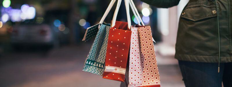 A close up of someone carrying Christmas present bags.