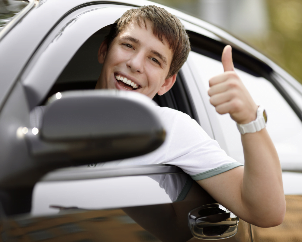 Person smiling and putting his thumb up whilst sat in his car