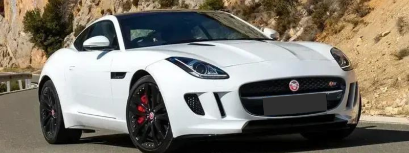 A white Jaguar F Type on a hillside road.