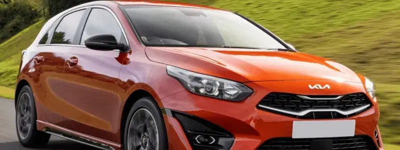 An orange Kia Ceed driving on a country road.