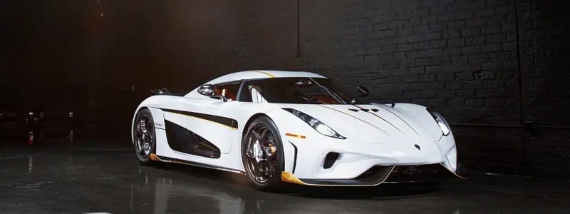 A white Koenigsegg parked in front of a black wall.