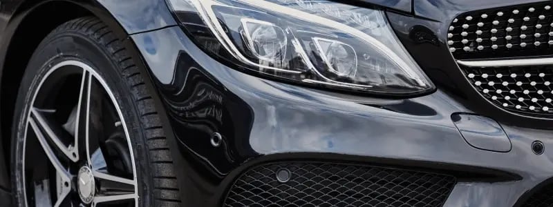 A close up of the side of a black Mercedes.