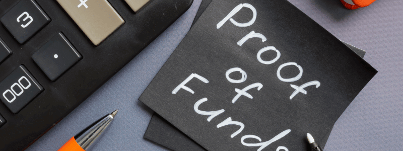 A black post it note with 'proof of funds' written on, next to a calculator and a pen.
