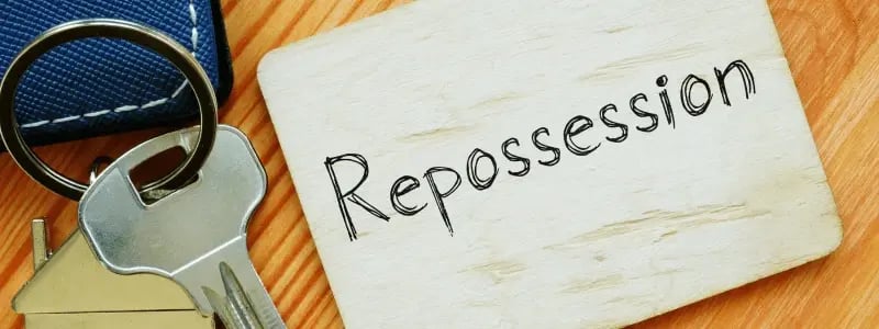 A repossession sign next to car and house keys.