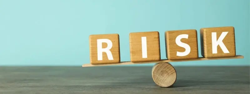 Letter blocks lined up to spell 'RISK', on top of a balancing ball. This represents the process of balancing risk.