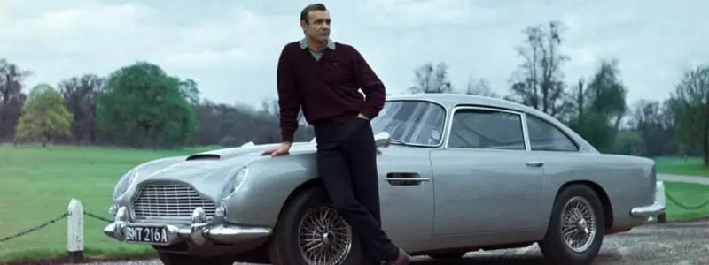 Sean Connery stood in front of the Aston Martin DB5.