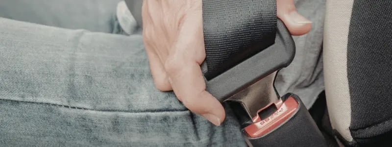 A close up of a person securing a seat belt in place.
