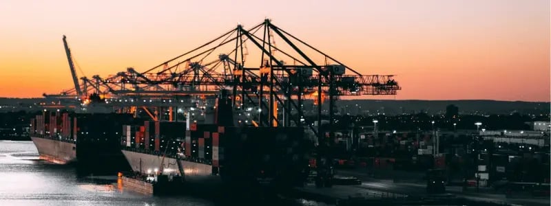 A look at a shipping dockyard, with sunset in the background.