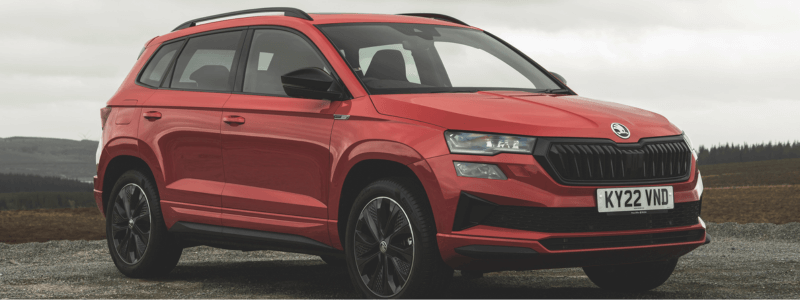 A red Skoda Karoq parked in a dark rural area.