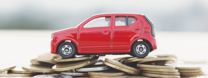 A red toy car sat on an uneven stack of coins.