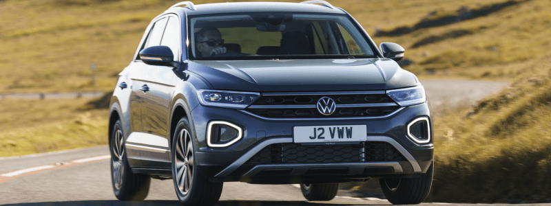 A grey VW T-Roc driving on an open country road.