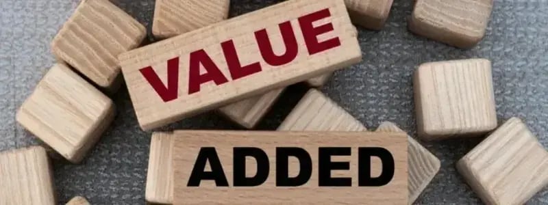 Small wooden blocks in a scattered pattern, with two larger blocks with writing on, spelling out 'VALUE' and 'ADDED'.