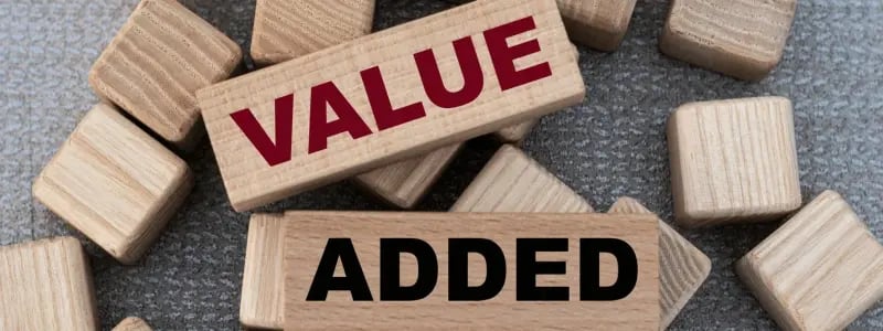 Small wooden blocks in a scattered pattern, with two larger blocks with writing on, spelling out 'VALUE' and 'ADDED'.