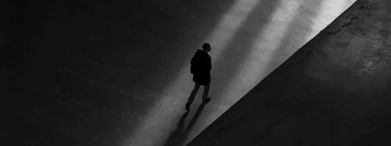 An overhead shot of a person walking in the dark, except for a light path made by external light.