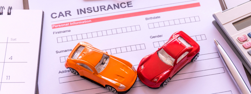 Two toy cars on top of a car insurance document.