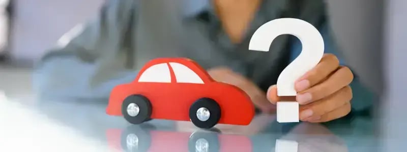 A person holding up a question mark next to a car cutout, symbolising car related questions.