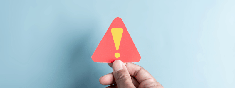 A person holding up a warning sign against a light blue background.