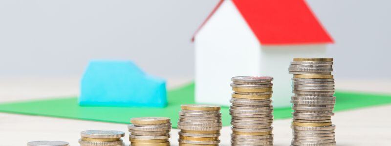A model house with stacks of coins in front.