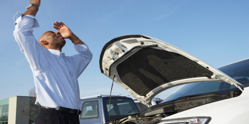 A person looks on frustrated, as their car is broken down, and likely written off.