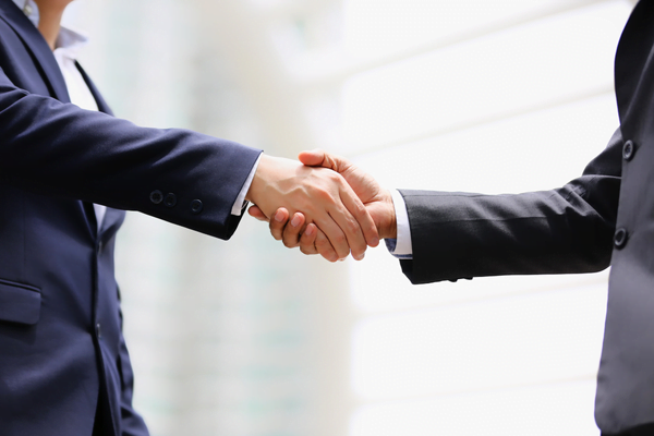Two business people shake hands in an office setting.