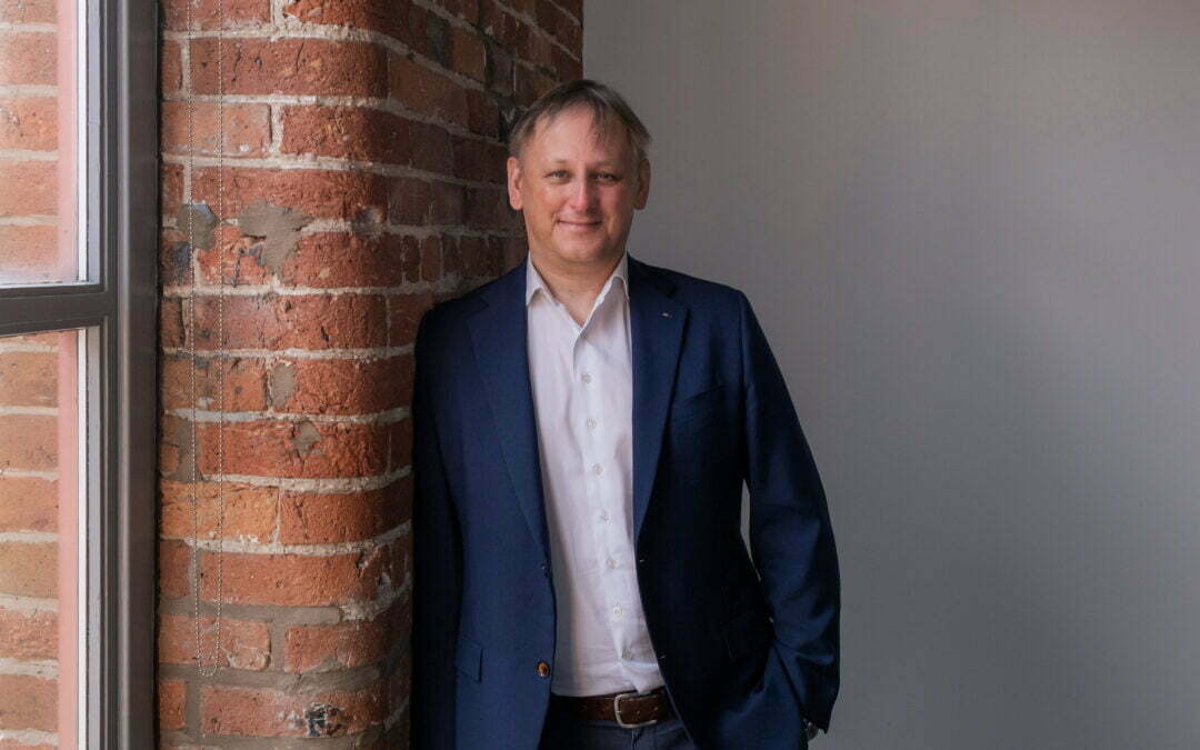 A photo of our Managing Director Andrew Marsh stood up leaning against a brick wall.