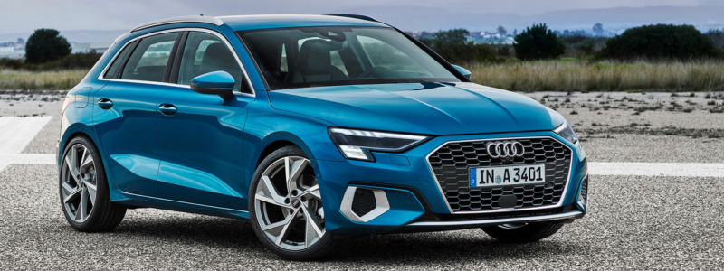 Teal blue A3 Sportback on a gravel surface with a natural landscape in the background.
