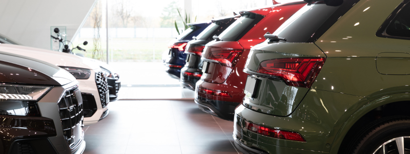 Row of new cars displayed in a car dealership showroom.
