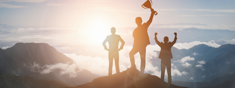 Business people stand on top of a mountain indicating success.