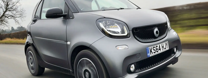 A grey Smart ForTwo on a road.