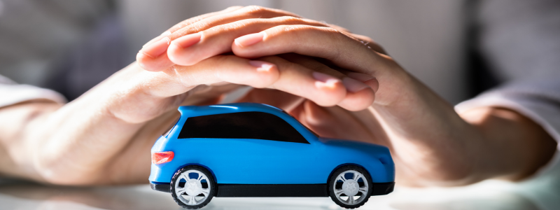 Hands over a toy car, depicting car insurance.